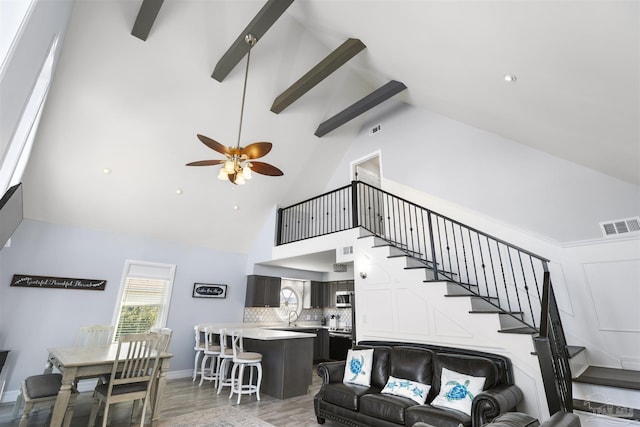 living room with ceiling fan, beam ceiling, high vaulted ceiling, and wood-type flooring