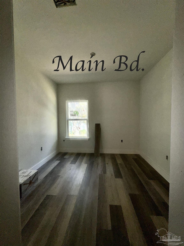 empty room featuring wood finished floors and baseboards