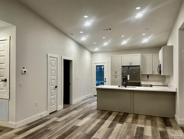 2020 Talbert St, Pensacola, FL 32507 - kitchen featuring black refrigerator with ice dispenser, a peninsula, wood finished floors, baseboards, and recessed lighting