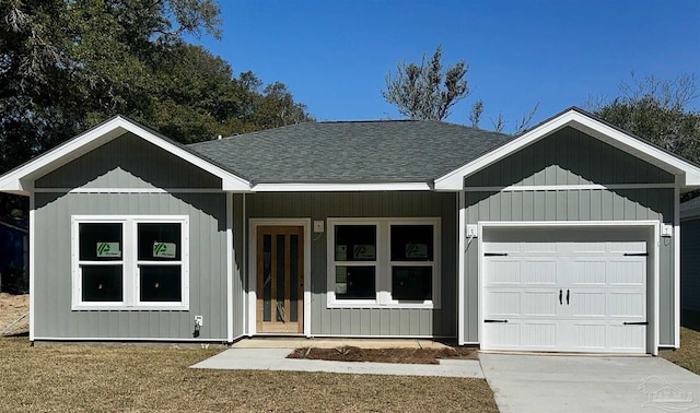 view of front of house featuring a garage, concrete driveway, and a shingled roof