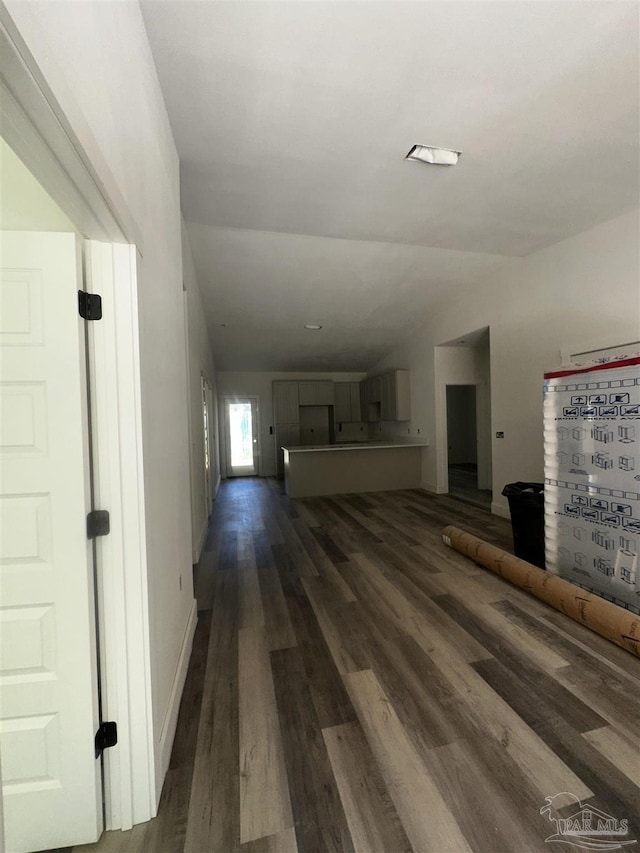 unfurnished living room featuring vaulted ceiling, baseboards, and wood finished floors