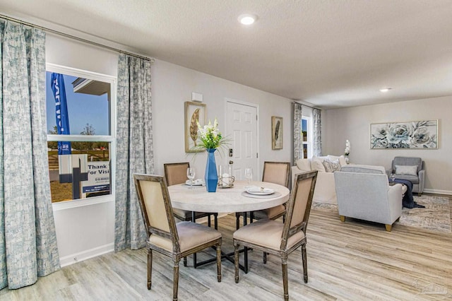 dining space with light hardwood / wood-style floors and a textured ceiling