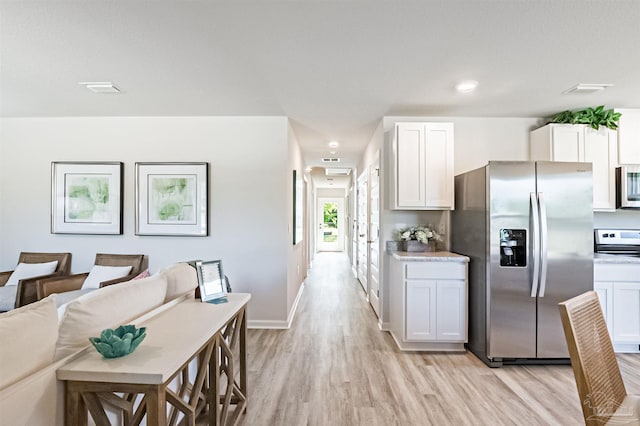 kitchen with stainless steel appliances, white cabinets, and light wood-type flooring