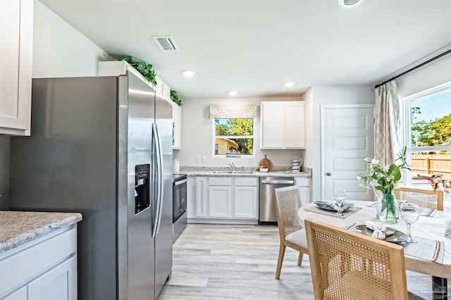 kitchen with white cabinetry, appliances with stainless steel finishes, sink, and a wealth of natural light