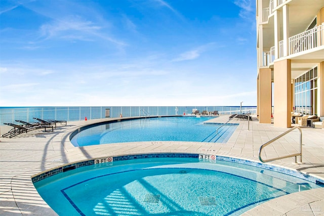 view of pool with a water view and a patio area