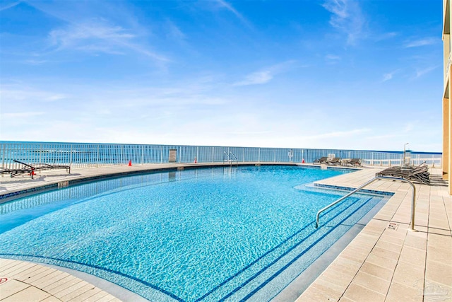 view of pool featuring a water view and a patio area