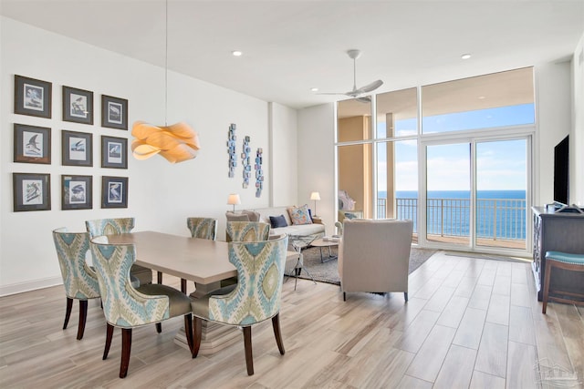 dining space featuring light hardwood / wood-style floors, a wall of windows, and ceiling fan