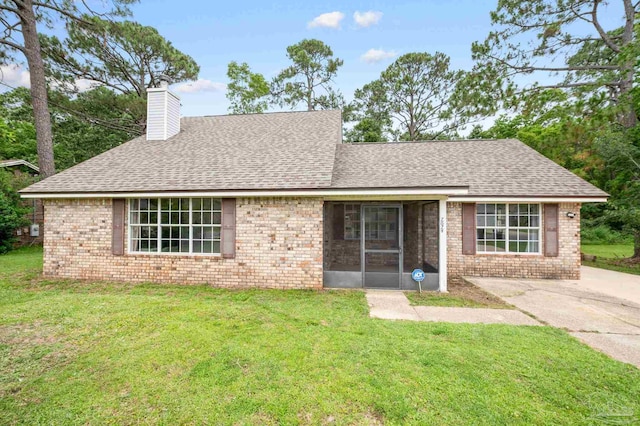 single story home featuring brick siding, a chimney, and a front yard