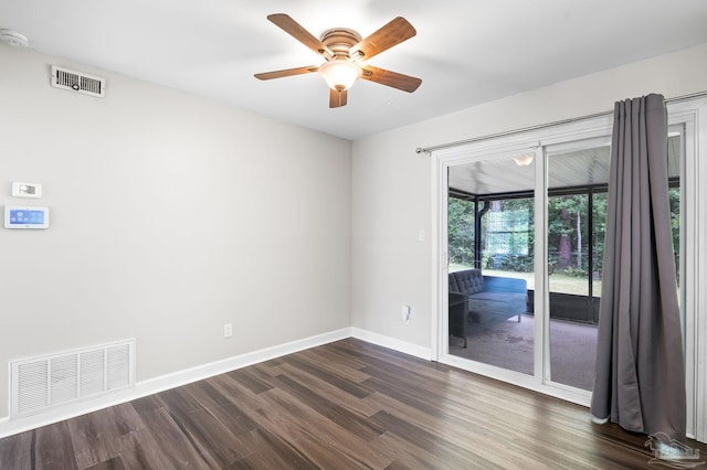 unfurnished room featuring a sunroom, dark wood-style flooring, visible vents, and baseboards