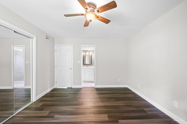 unfurnished bedroom featuring baseboards, visible vents, ensuite bath, and wood finished floors