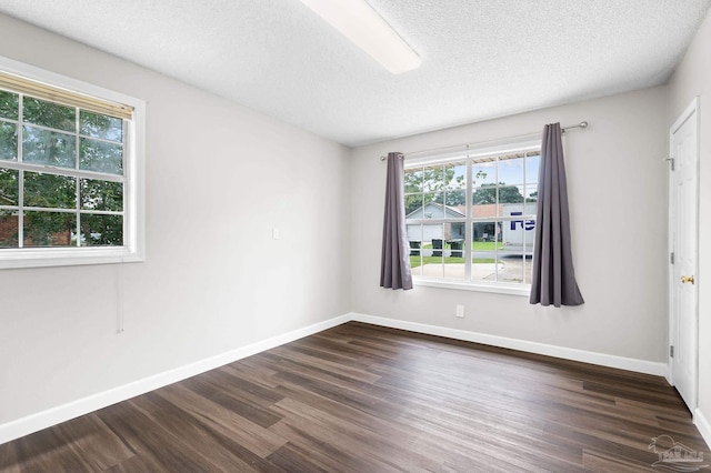 unfurnished room featuring baseboards, dark wood finished floors, and a textured ceiling