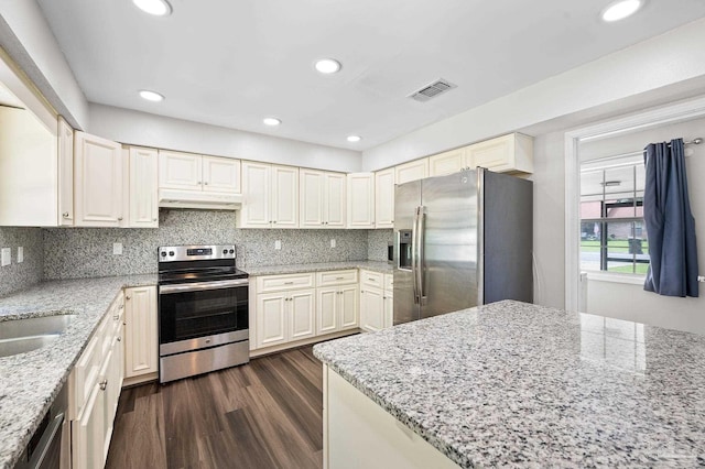 kitchen with dark wood-style floors, stainless steel appliances, tasteful backsplash, visible vents, and under cabinet range hood