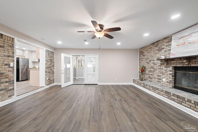 unfurnished living room featuring a fireplace, french doors, ceiling fan, and hardwood / wood-style floors