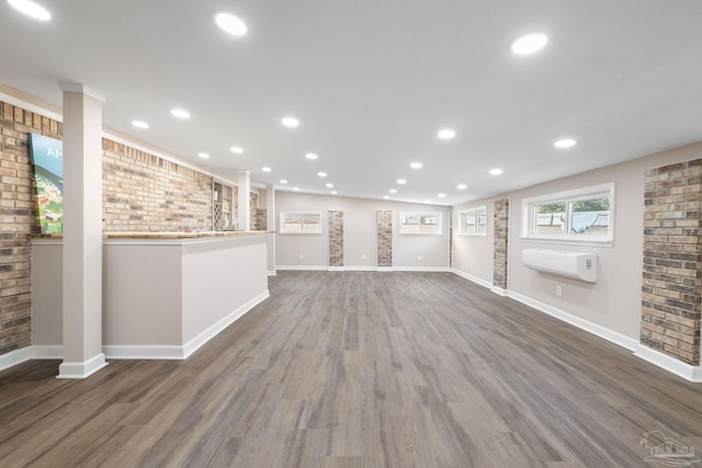 interior space with brick wall, an AC wall unit, and dark hardwood / wood-style flooring