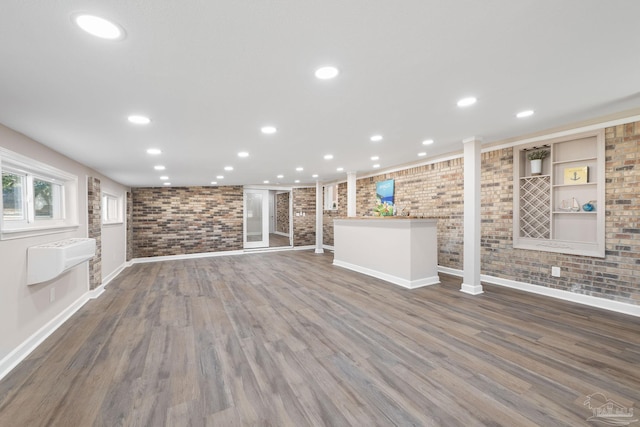 unfurnished living room with a wall unit AC, dark hardwood / wood-style floors, and brick wall