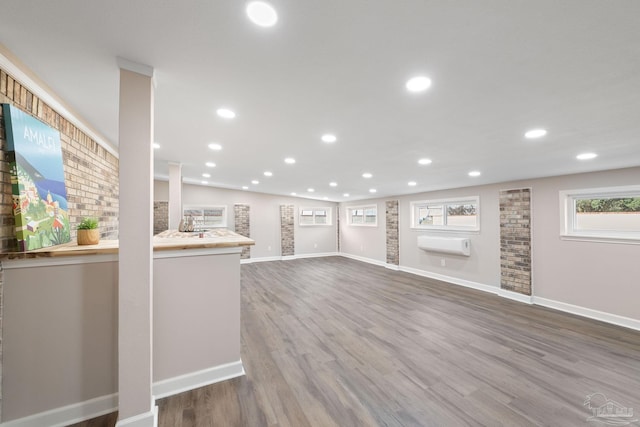 unfurnished living room with vaulted ceiling, a wall mounted air conditioner, and hardwood / wood-style floors