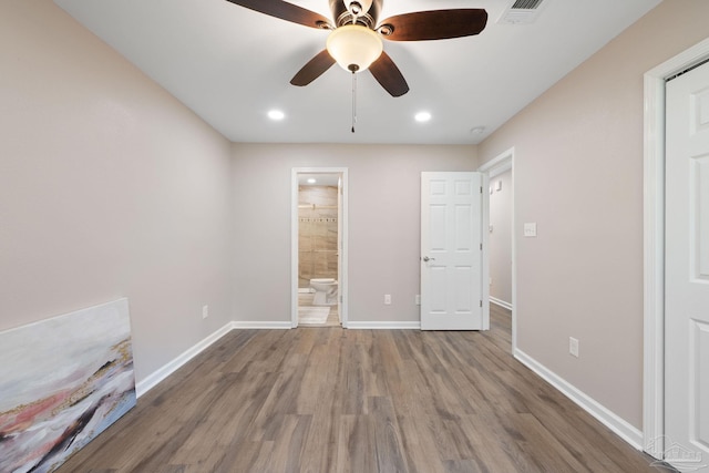 unfurnished bedroom with ensuite bath, ceiling fan, and wood-type flooring