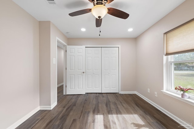 unfurnished bedroom with dark hardwood / wood-style flooring, a closet, and ceiling fan