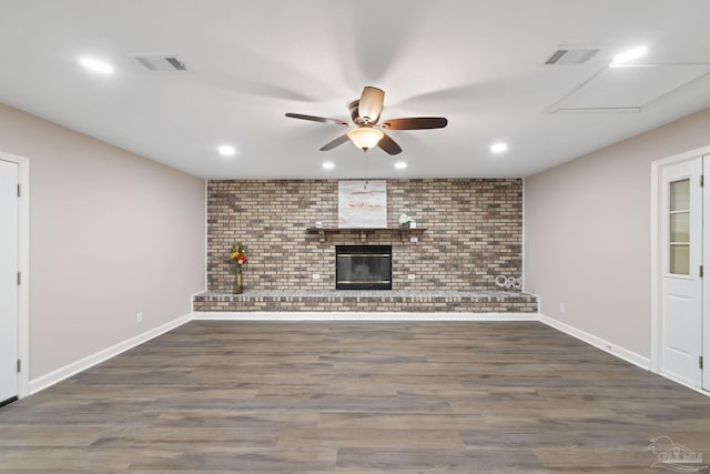 unfurnished living room featuring brick wall, a fireplace, ceiling fan, and dark hardwood / wood-style floors