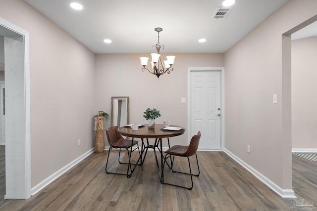 dining area with hardwood / wood-style flooring and a notable chandelier