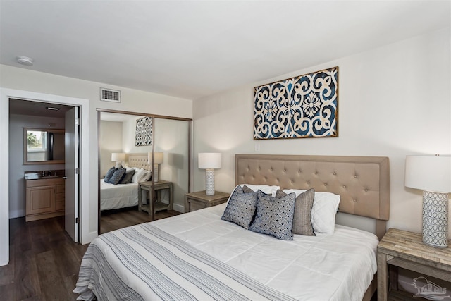 bedroom featuring a closet, ensuite bathroom, and dark hardwood / wood-style flooring