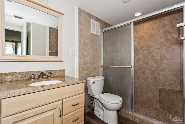 bathroom featuring a shower with door, hardwood / wood-style floors, vanity, and toilet