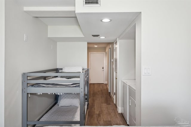 bedroom with dark hardwood / wood-style floors and washer and dryer