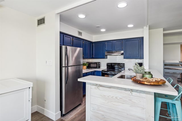 kitchen featuring black appliances, sink, kitchen peninsula, a kitchen bar, and blue cabinets