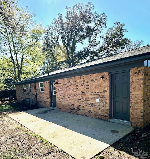 exterior space with a patio, brick siding, central AC unit, and fence