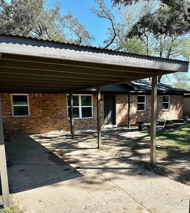 back of house featuring an attached carport, brick siding, and driveway