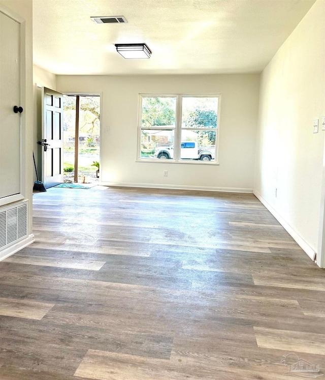 spare room with visible vents, baseboards, and wood finished floors