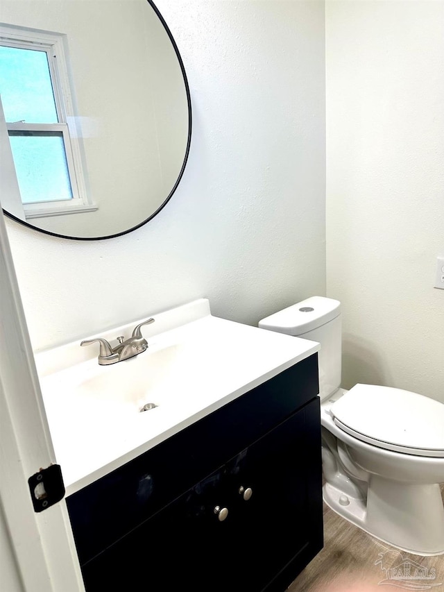 half bathroom featuring toilet, vanity, and wood finished floors