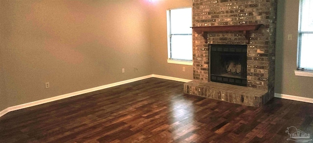 unfurnished living room with a fireplace, a wealth of natural light, and dark hardwood / wood-style flooring