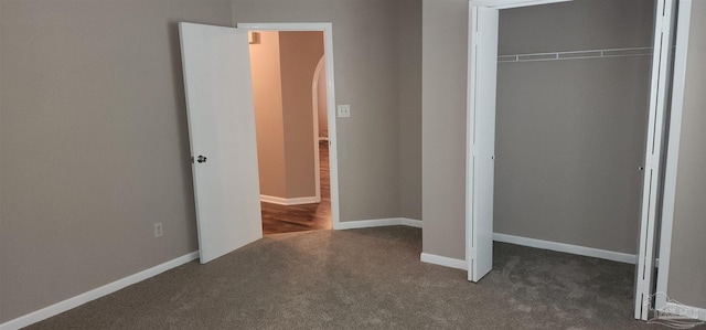 unfurnished bedroom featuring dark colored carpet and a closet