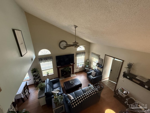 1515 Mariners Cir, Gulf Breeze, FL 32563 - living room featuring a textured ceiling, high vaulted ceiling, a ceiling fan, a fireplace with flush hearth, and wood finished floors