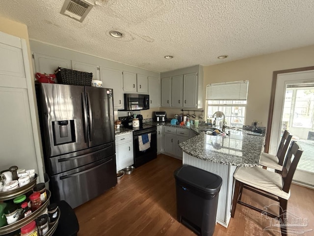 1515 Mariners Cir, Gulf Breeze, FL 32563 - kitchen featuring black appliances, a peninsula, a sink, a textured ceiling, and dark wood-type flooring