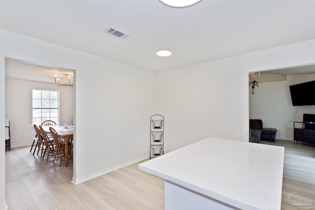 kitchen with light wood finished floors, baseboards, visible vents, and light countertops