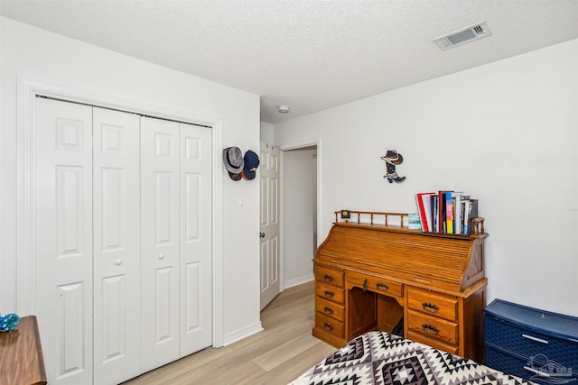 home office with light wood-style floors, visible vents, and a textured ceiling