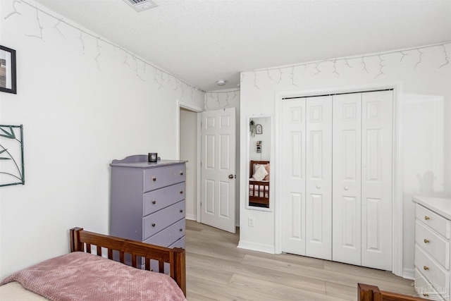 bedroom featuring light wood-style floors, a closet, and visible vents