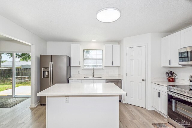 kitchen featuring a kitchen island, stainless steel appliances, white cabinetry, and sink