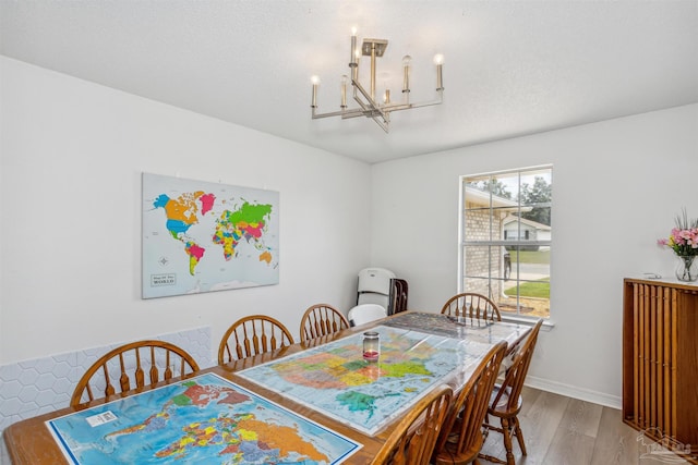 dining area with baseboards, a textured ceiling, an inviting chandelier, and wood finished floors