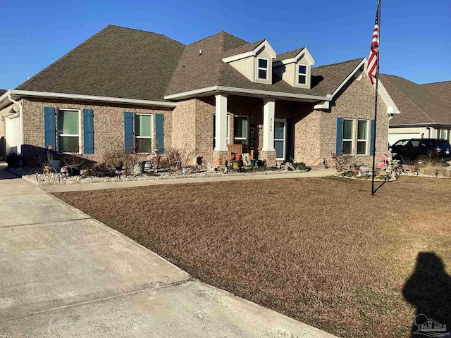 view of front of property with covered porch, a shingled roof, and brick siding