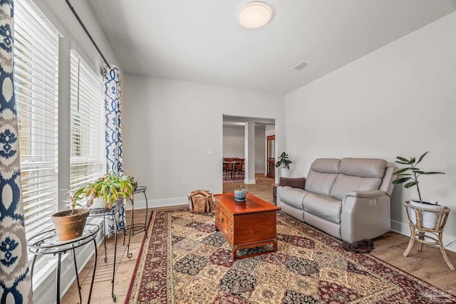 living area with light wood-type flooring, visible vents, and baseboards