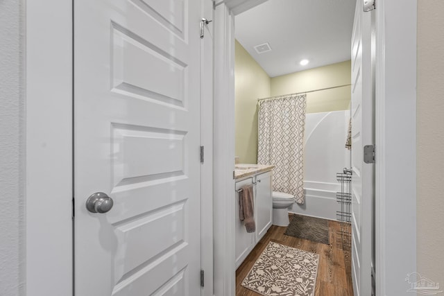 full bathroom featuring shower / bath combination with curtain, visible vents, toilet, vanity, and wood finished floors