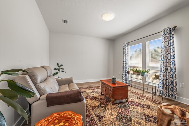 living area featuring baseboards, visible vents, and wood finished floors