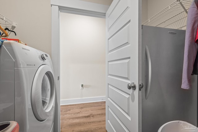 clothes washing area with laundry area, washer / clothes dryer, wood finished floors, and baseboards