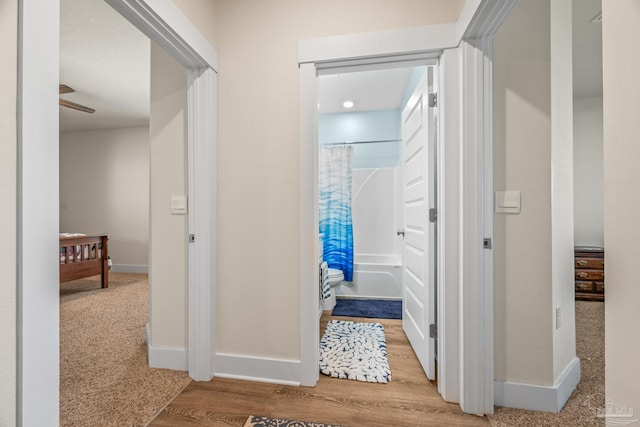 hall with baseboards and wood finished floors