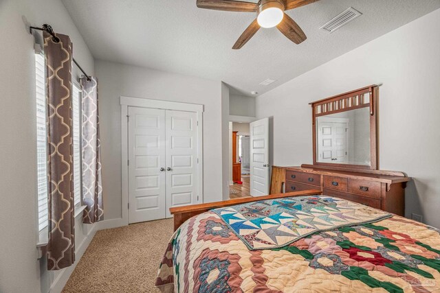 carpeted bedroom with visible vents, ceiling fan, vaulted ceiling, a textured ceiling, and a closet