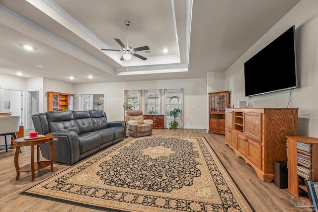 living area featuring a ceiling fan, a tray ceiling, light wood-style flooring, and recessed lighting