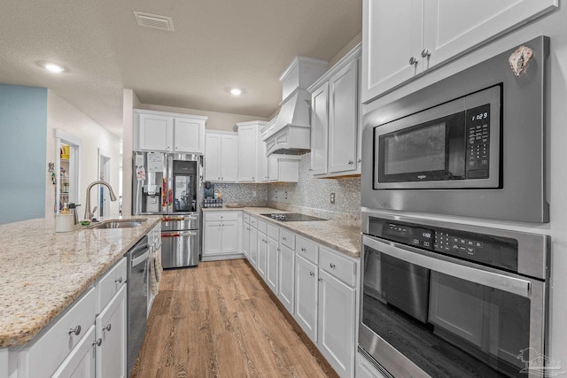 kitchen featuring light wood finished floors, visible vents, decorative backsplash, appliances with stainless steel finishes, and a sink